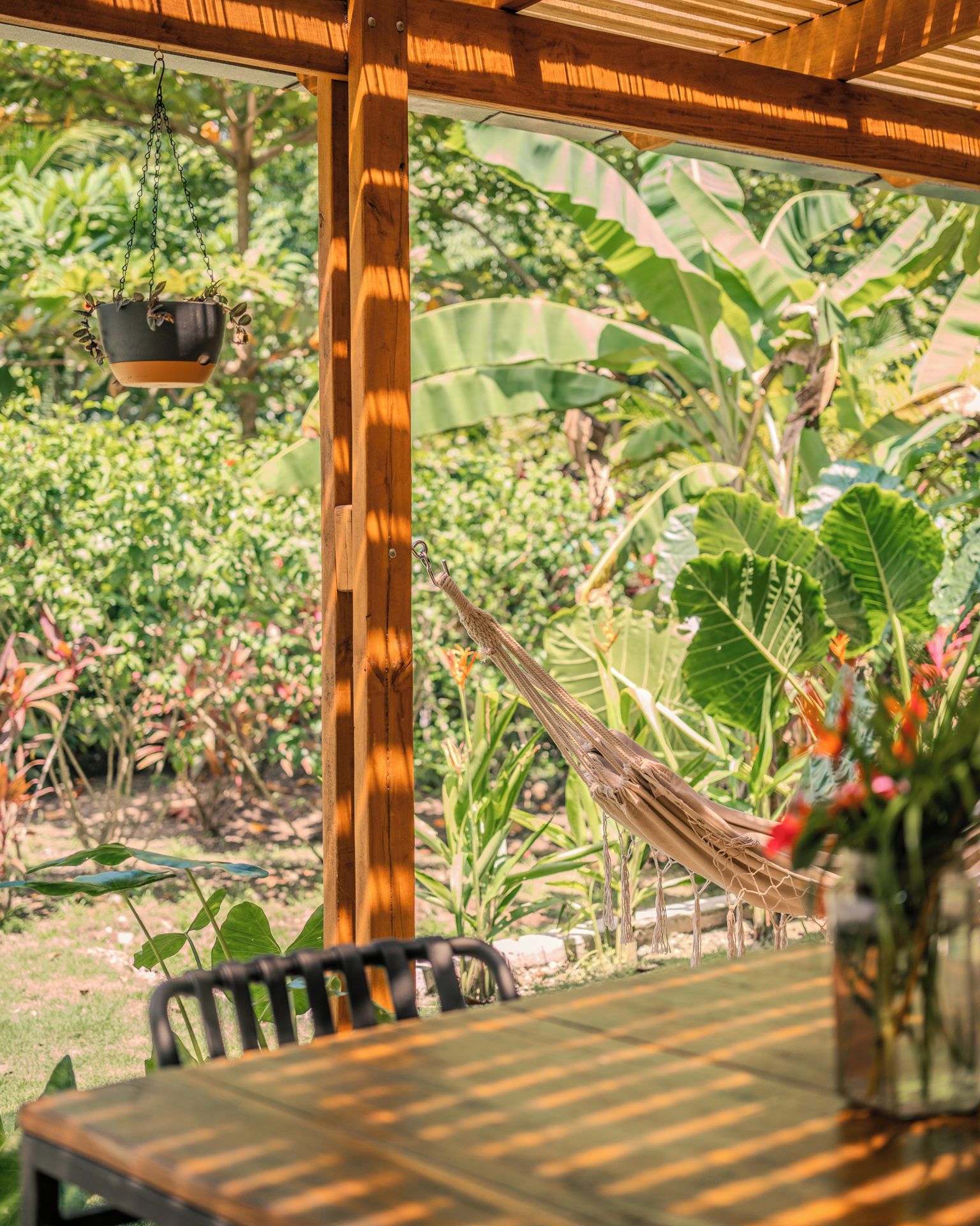 A wooden pergola with a hanging planter and a hammock.
