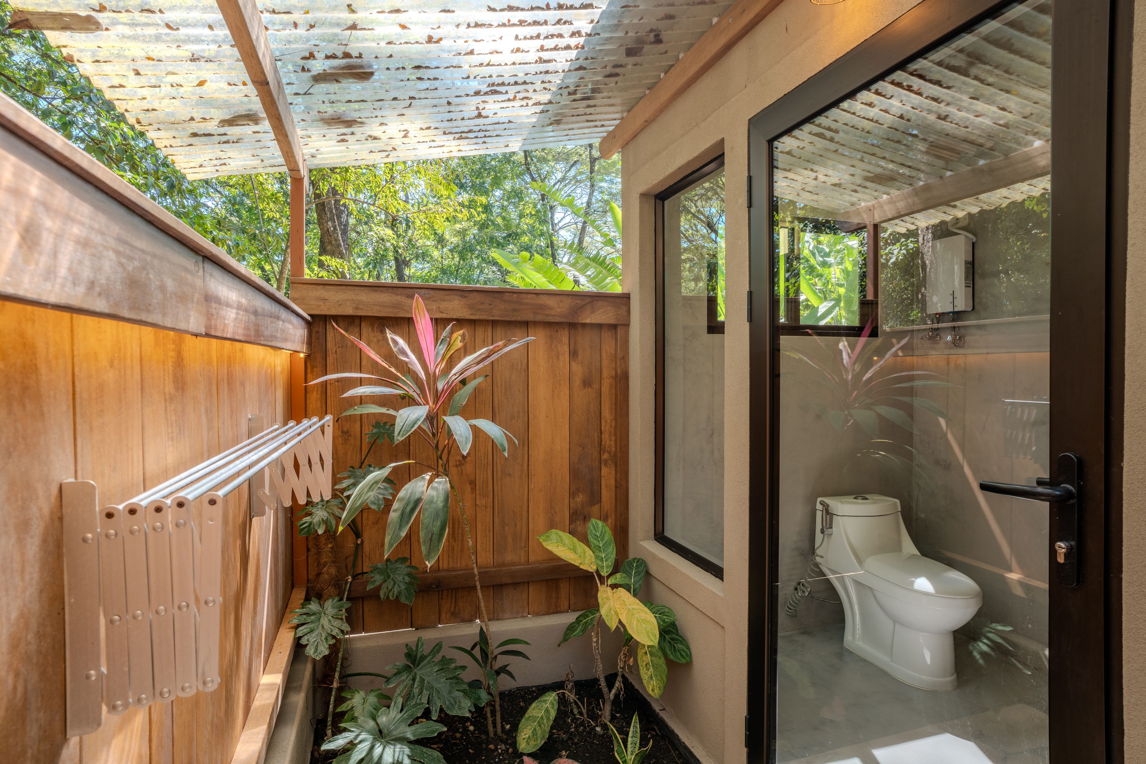 Une petite salle de bain comprenant des toilettes, un mur en bois et une porte en verre donnant accès à une zone douche.