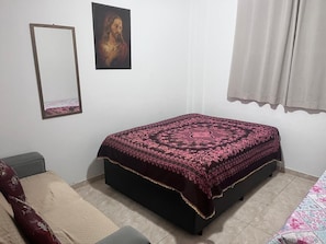 A bedroom with a bed, a chair, a bedside table, a mirror, and a painting on the wall. - Suitable for weekends and holidays, very close to the beach - Vila Guilhermina (Praia Grande)