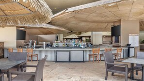 Uma área de bar ao ar livre com balcão, banquetas e um quadro de menu com a inscrição