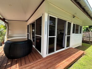 Une terrasse couverte avec un jacuzzi, des portes-fenêtres coulissantes et une terrasse en bois.