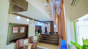A reception area with a desk, chairs, clocks, and a chandelier. - Banky Hotel & Suites (Ado Ekiti)