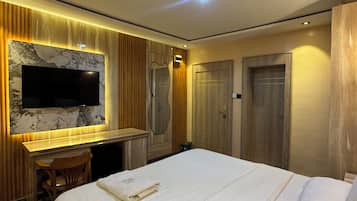 Ein Hotelzimmer mit einem Bett, einem Schreibtisch, einem Fernseher und einem Kleiderschrank.