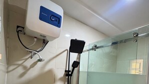A glass-enclosed shower with a handheld showerhead and a wall-mounted control panel. - Banky Hotel & Suites (Ado Ekiti)