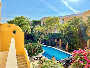 Un espace piscine avec des chaises longues et un escalier menant à un bâtiment à la façade jaune.