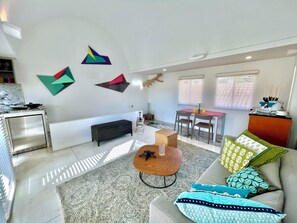 A modern living room with a sofa, coffee table, and a dining area with a table and chairs. - by Calamari.Homes - Centenario Casa 206 - Old City (Cartagena de Indias)