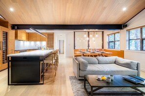 Une cuisine moderne dotée d’un îlot central, de meubles en bois et d’un coin repas avec un canapé et une table.