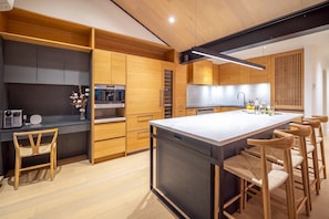 Une cuisine moderne dotée d’un îlot central, de meubles en bois et de tabourets de bar.