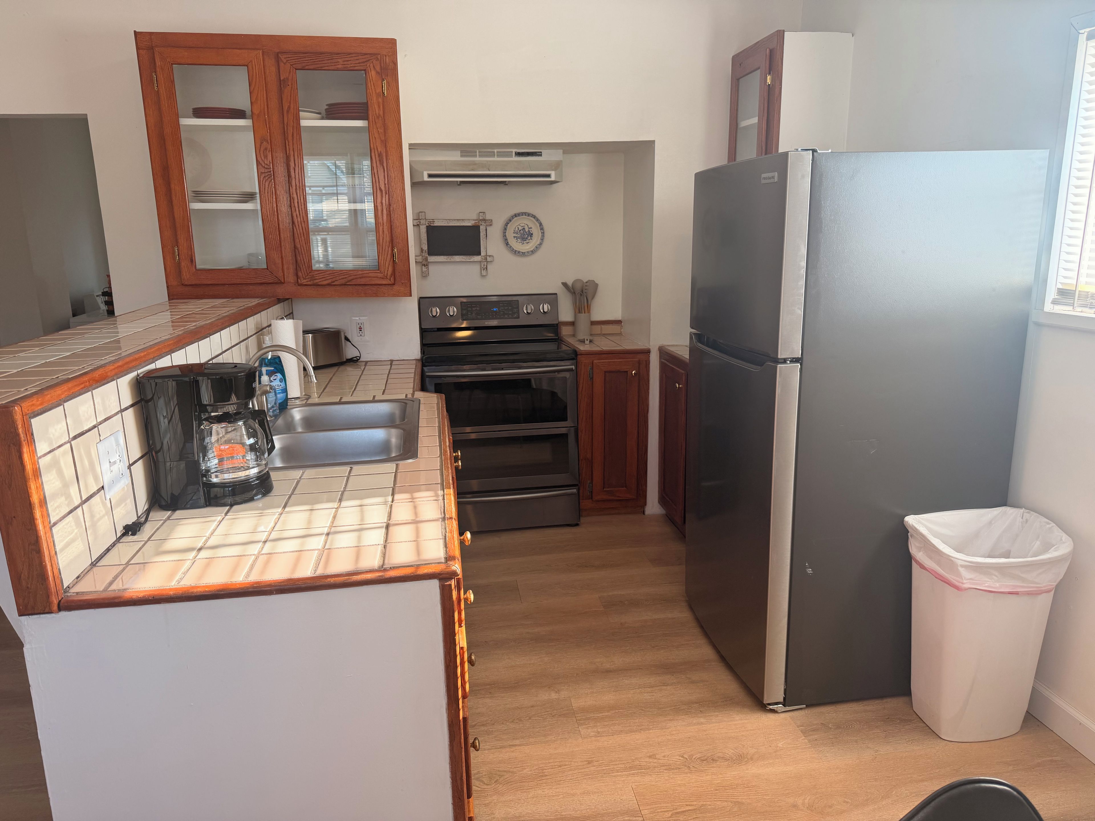 A kitchen with a coffee maker, oven, and a refrigerator.
