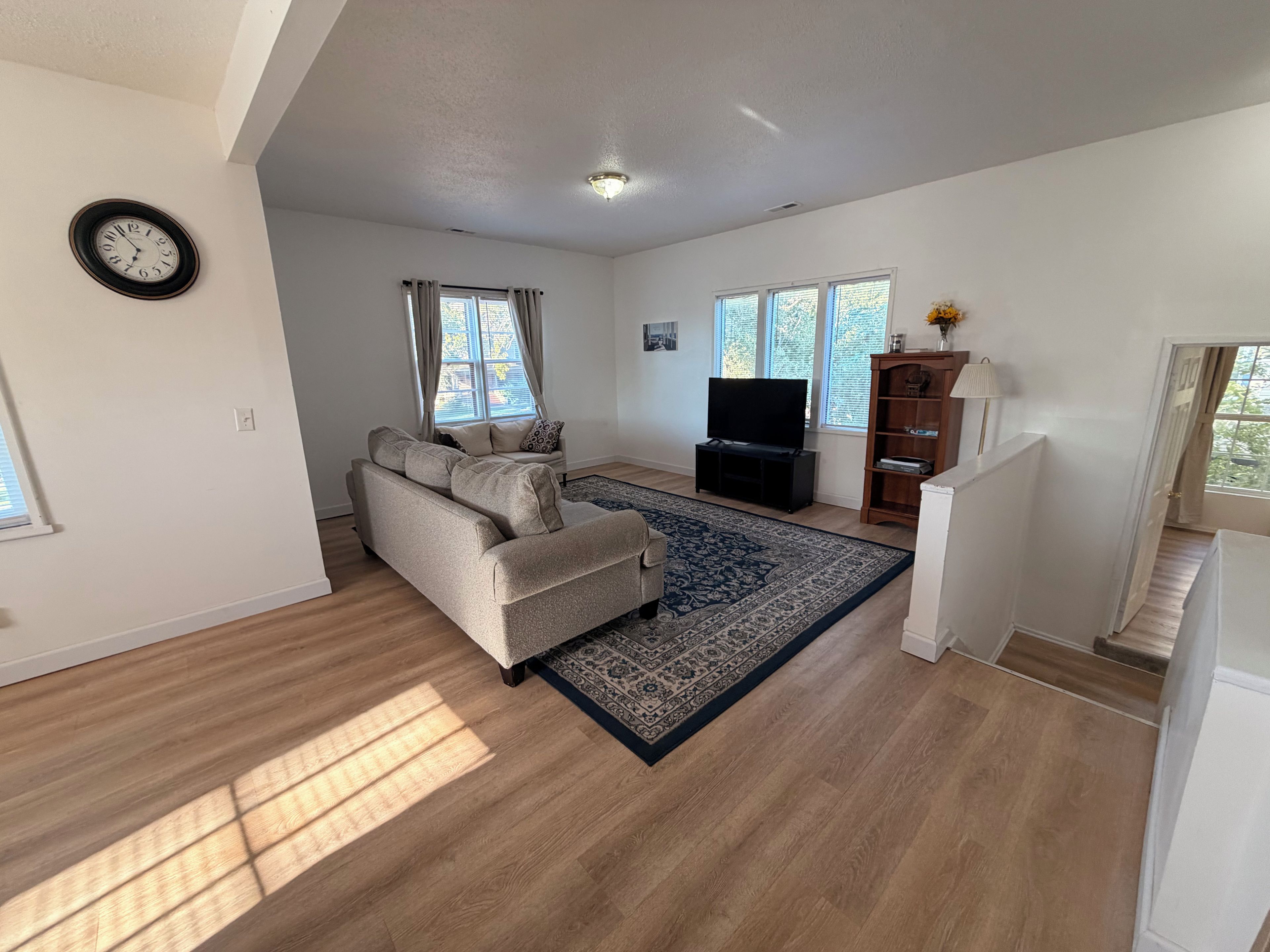 Un salon avec un canapé, un téléviseur, un tapis et un escalier.