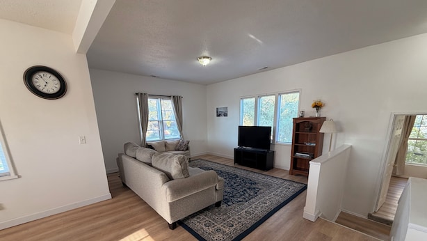 A living room with a sofa, a television, a rug, and a staircase. - Beautiful 2-bedroom apartment with AC in charming Hutchinson (Hutchinson)