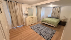 A bedroom with a bed, a dresser, a mirror, and a patterned rug. - Beautiful 2-bedroom apartment with AC in charming Hutchinson (Hutchinson)