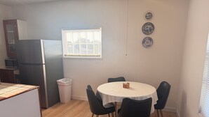 A compact kitchen with a refrigerator, microwave, and a dining area with a round table and chairs. - Beautiful 2-bedroom apartment with AC in charming Hutchinson (Hutchinson)