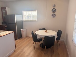 Eine kompakte Küche mit Kühlschrank, Mikrowelle und einer Essecke mit rundem Tisch und Stühlen.