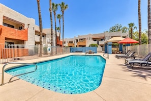A swimming pool with a metal ladder, surrounded by palm trees and lounge chairs. - Near ASU • King Bed • Arcade • Pool/Spa • Sleeps 8 • Pets • 65" TV • W/D (Tempe)