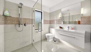 Ein modernes Badezimmer mit Duschkabine aus Glas, Toilette und Waschtisch mit Spiegel.