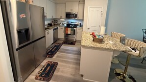 Een moderne keuken met roestvrijstalen apparatuur, een granieten aanrechtblad en een bar met een comfortabele stoel.