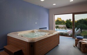 Boblebad i et rum med udsigt til swimmingpool og grønne områder.