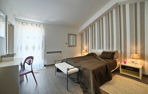 Ein Schlafzimmer mit Bett, Nachttisch, Stuhl und einem Fenster mit Vorhängen.
