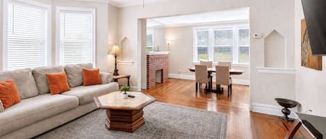 Una sala de estar con sofá, mesa de centro y comedor con sillas y mesa.