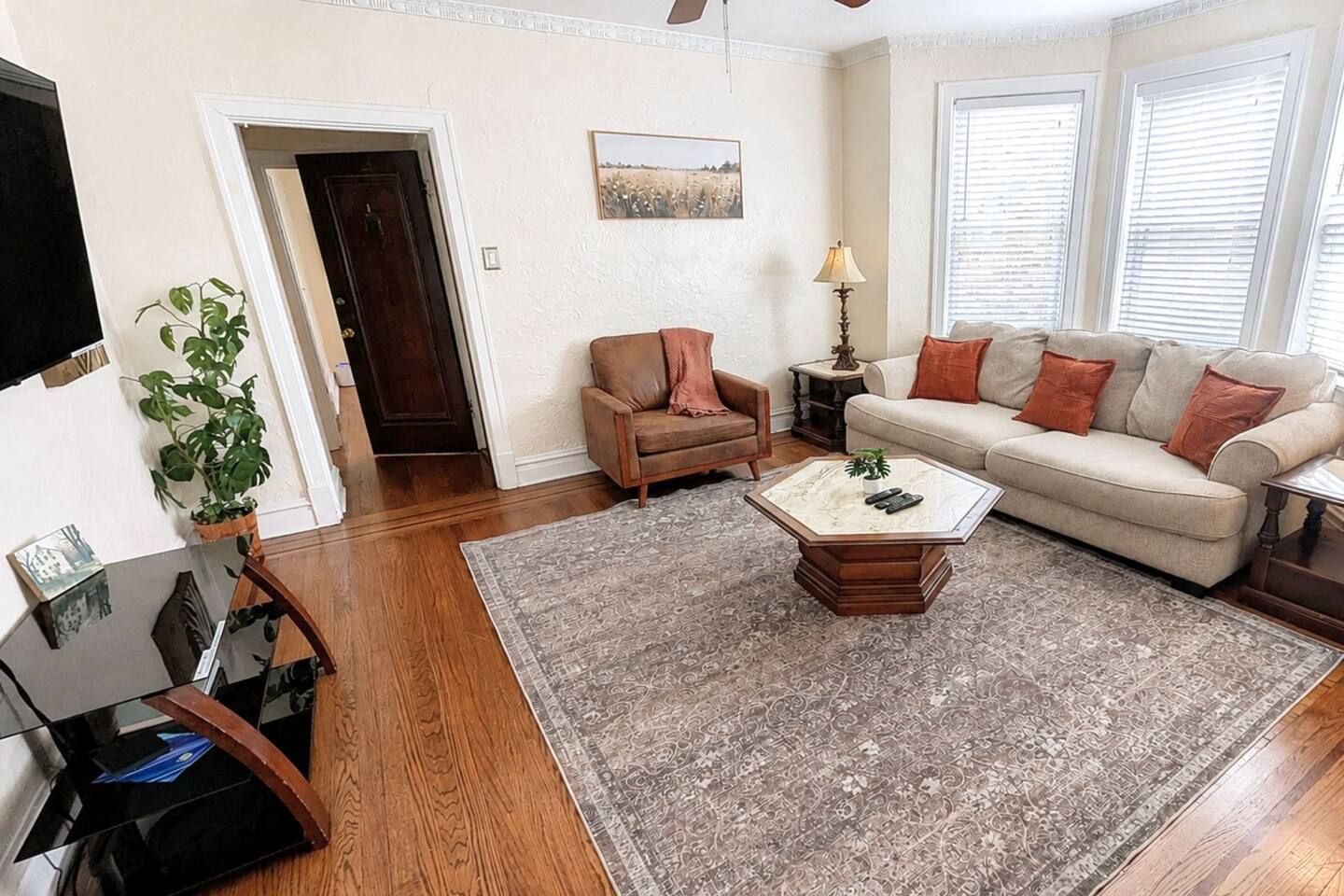 Una sala de estar con sofá, sillón, mesa de centro y televisor.