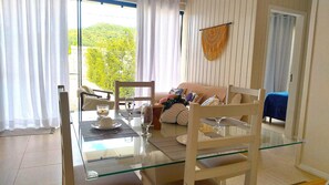Un coin repas avec une table en verre, des chaises et un canapé agrémenté de coussins.