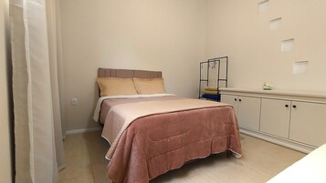 A bedroom with a bed, a bedside table, a wardrobe, and a mirror.