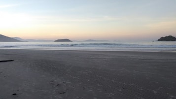 Una playa con arena, agua tranquila y islas al fondo.