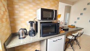 Cocina compacta con microondas, tostadora, hervidor y licuadora sobre la encimera.