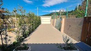 Un chemin menant à une entrée fermée par un portail, avec un ciel dégagé au-dessus.