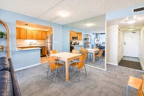 Un espacio habitable compacto con kitchenette, una zona de comedor con sillas, un sofá y un espejo que refleja la habitación.