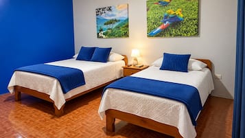 Una habitación de hotel con dos camas, una mesita de noche con una lámpara y dos cuadros colgados en la pared.