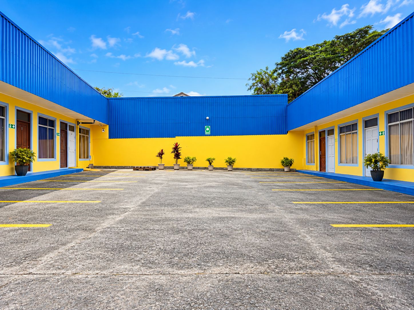 Un hotel con un patio central, varias habitaciones a cada lado y una decoración en tonos azul y amarillo.