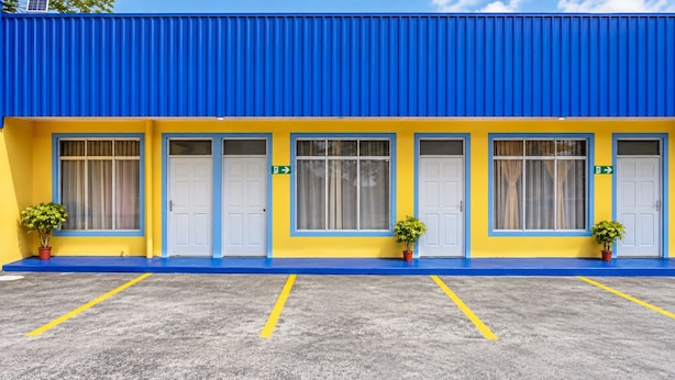 Ein Gebäude mit blauem Dach und gelben Wänden, mit vier weißen Türen und Blumentöpfen.