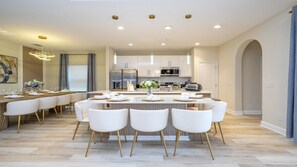 A modern kitchen with white cabinetry, stainless steel appliances, and a central island with seating. - Cozy 6BR Balmoral Retreat, Pool, Spa & Waterpark (Haines City)