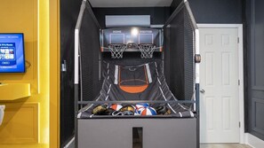 Eine Basketball-Spielhalle mit zwei Körben, einem Bildschirm und einer Tür.