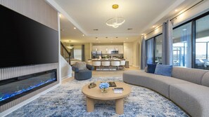 Un salon moderne avec un téléviseur à écran plat, une cheminée, un canapé et une table basse.