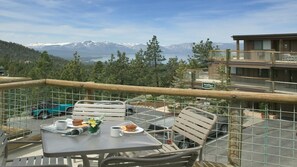 A balcony with a table set for two, overlooking a mountainous landscape with a view of snow-capped peaks and a body of water. - 2BR Tahoe 3 Suite at WorldMark Lake Tahoe Near Heavenly Ski Resort (Stateline)