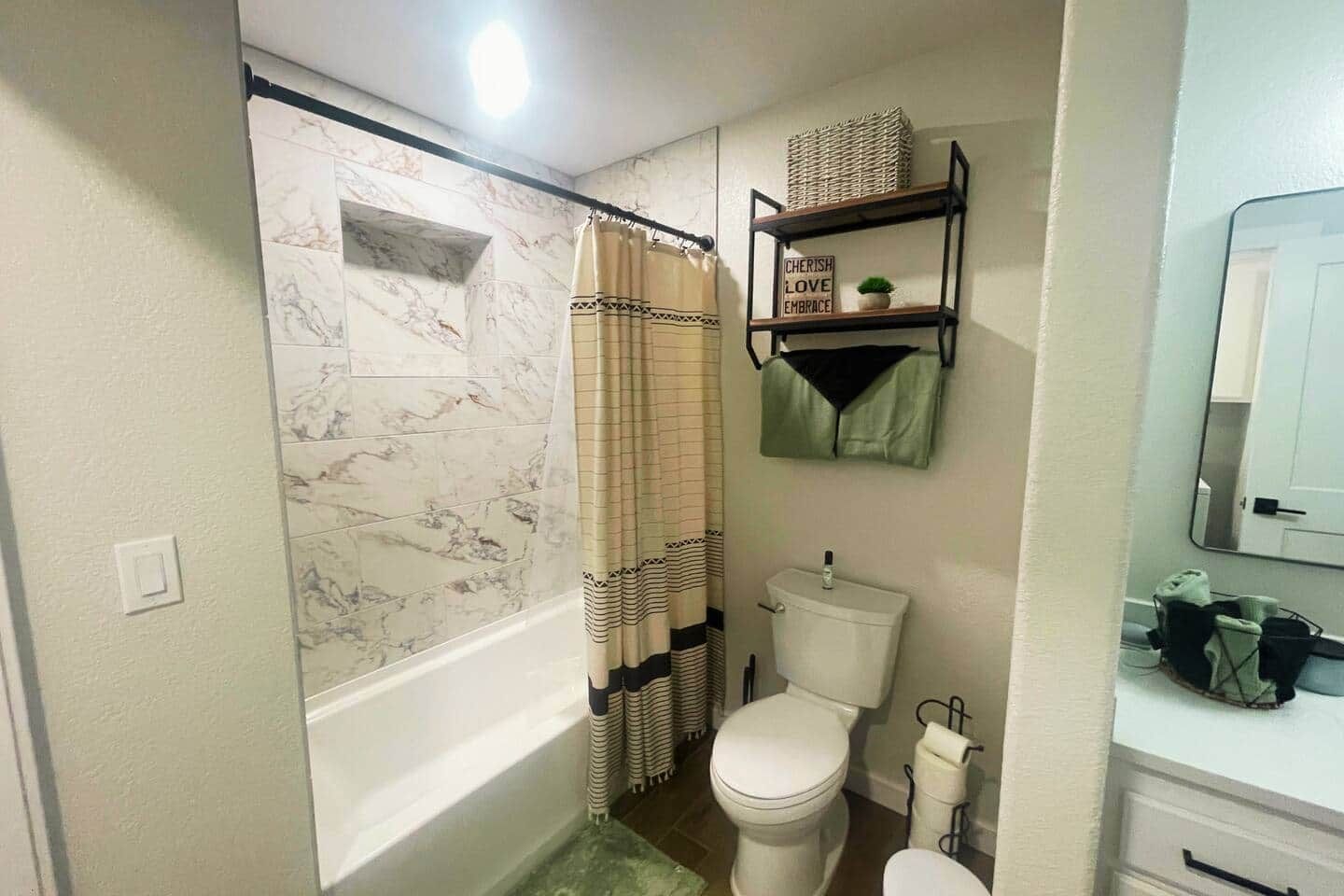 A bathroom with a bathtub, toilet, and a shelf with a sign.