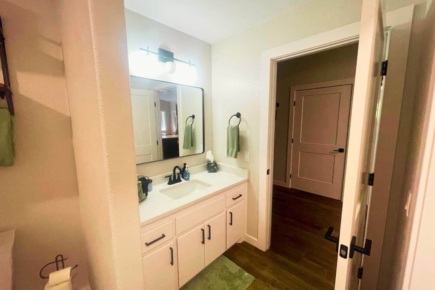 Un baño con lavamanos doble, un espejo y una puerta que da a otra habitación.