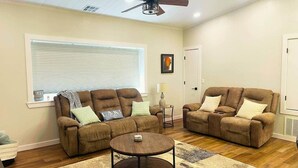 Un salon avec deux canapés marron, une table basse ronde et un ventilateur de plafond.