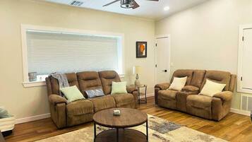 A living room with two brown sofas, a round coffee table, and a ceiling fan.