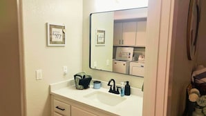 Une salle de bain avec un lavabo blanc, un miroir, un porte-serviettes et un lave-linge.