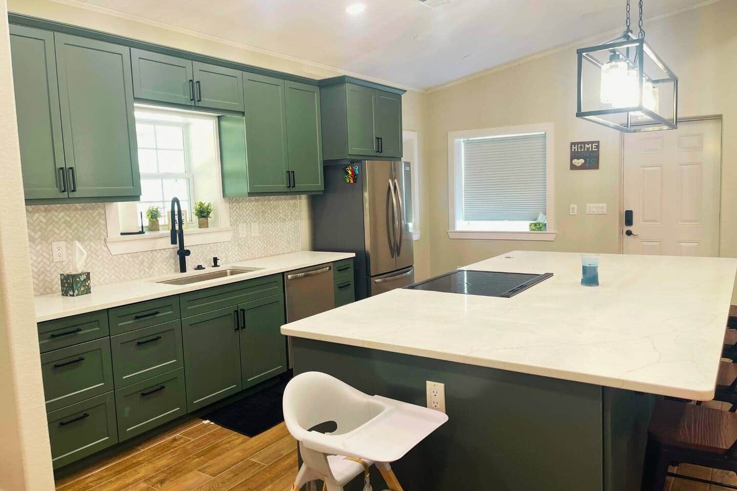 Cozinha moderna com armários verdes, ilha central e lava-louças embutida.