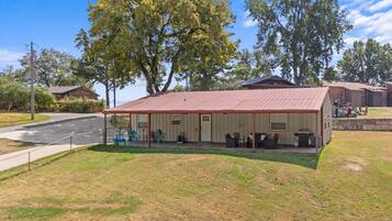 A single-story building with a covered patio area, a fenced yard, and a road in the background.