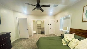 Une chambre à coucher comprenant un lit, une commode, un placard et un ventilateur de plafond.