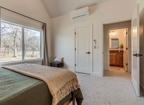 A bedroom with a bed, a window, an air conditioning unit, a door, and a view of the outside. - Sunset Point: Waterfront Home w/ amazing lake views, large deck, and hot tub! (Texanna)
