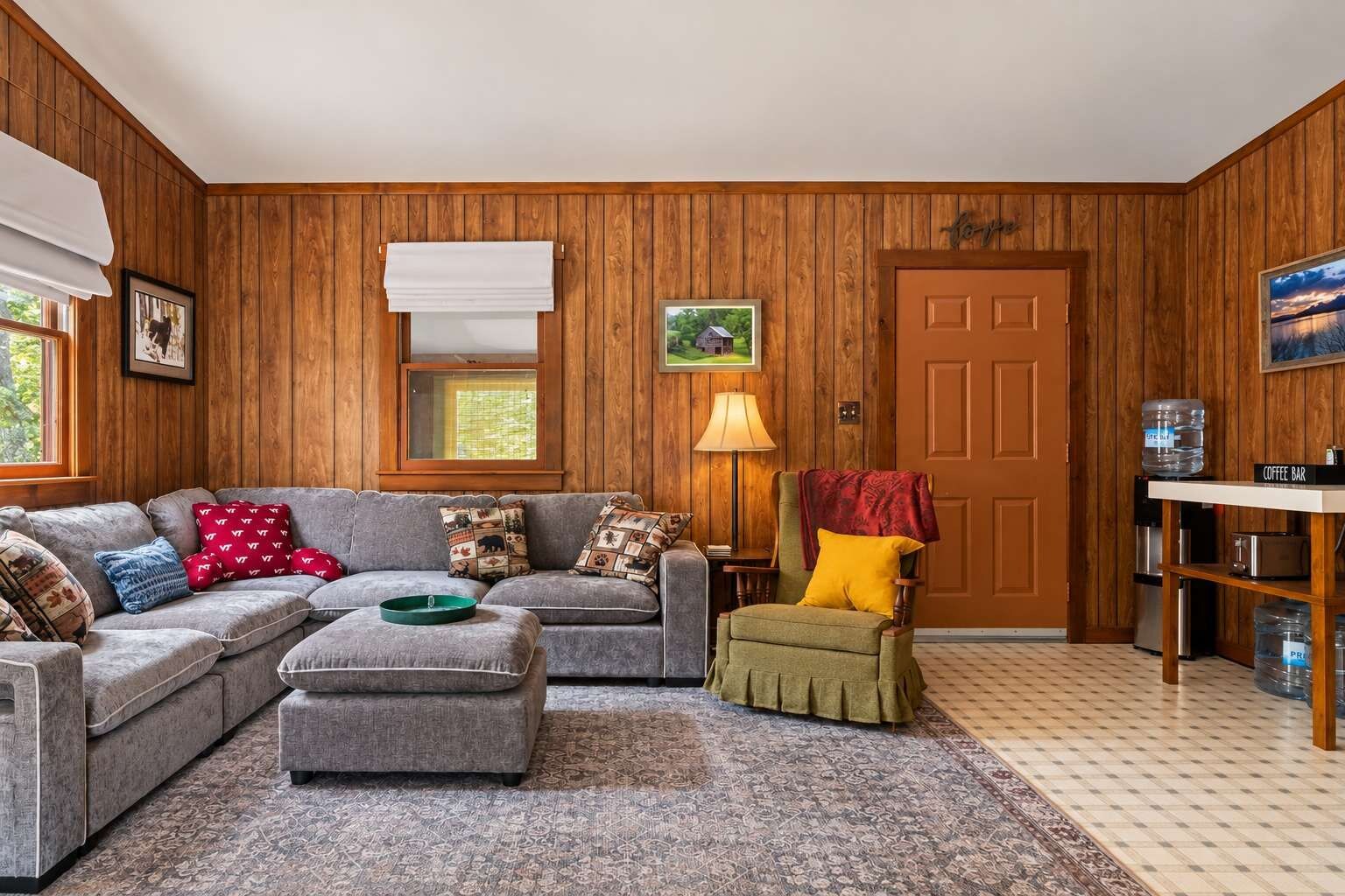 A cozy living room with a sectional sofa, a coffee bar, and a door with a picture of a house.
