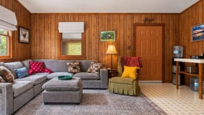 Una sala de estar acogedora con un sofá modular, una barra para café y una puerta con una imagen de una casa.