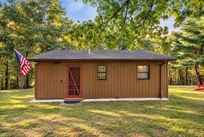 A small wooden cabin with a red door, a flag, and a window.